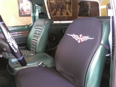 1978 Ford Bronco - Interior of a green vehicle a tribal cross seat cover and a Beatles Abbey Road poster on the rear window.