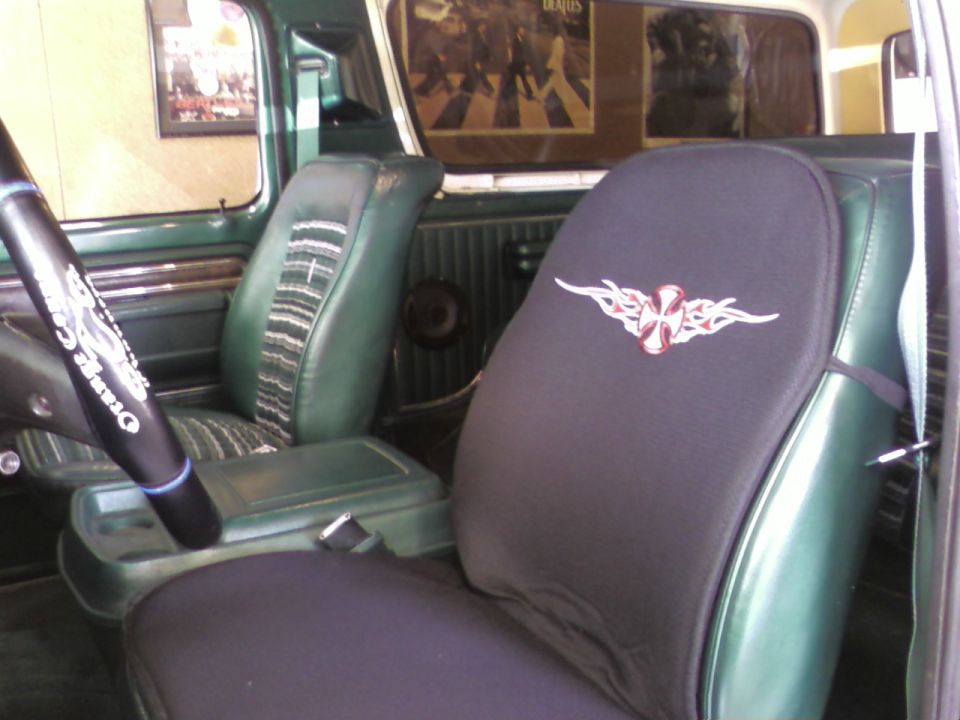 Interior view of green vehicle with tribal cross seat cover and Beatles poster
