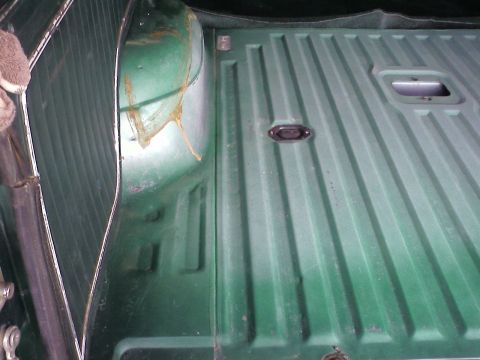1978 Ford Bronco - Close-up view of the interior of a green truck bed, showing the ribbed floor and a tie-down anchor.