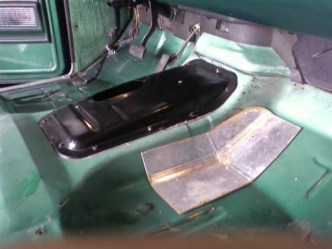 1978 Ford Bronco - Close-up of a vehicle's interior floor, showing the transmission tunnel and a metal patch.
