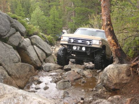 1989 Ford Bronco - This modified SUV navigates a challenging rocky terrain, demonstrating its off-road capabilities.