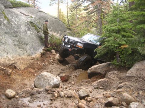 1989 Ford Bronco - A black SUV navigates a challenging off-road trail with steep inclines and large rocks.