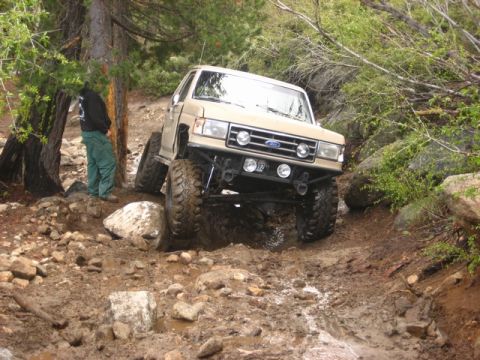 1989 Ford Bronco - Ford Bronco tackling a challenging off-road course with mud and rocks.