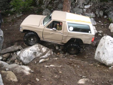 1989 Ford Bronco - This 1989 Ford Bronco is shown tackling a challenging off-road course with large rocks and mud.