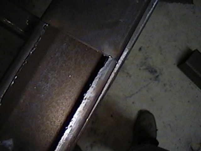Metal fabrication with visible welds and rust, on a concrete floor
