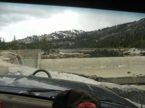 1989 Ford Bronco - Scenic view of a dam and lake with mountains in the background, seen from a vehicle.
