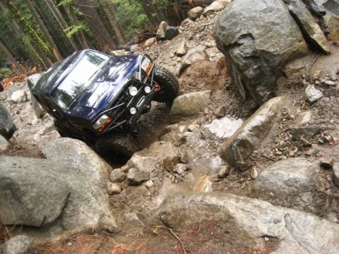 1989 Ford Bronco - This modified SUV is tackling a challenging rocky terrain, demonstrating its off-road capabilities.