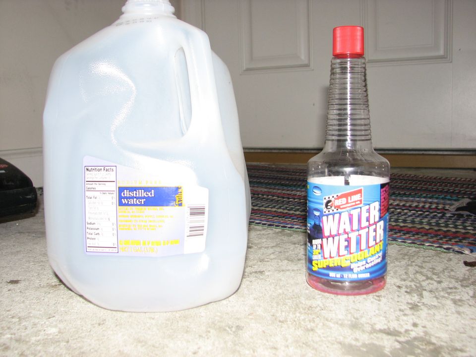 gallon jug of distilled water next to a bottle of Red Line Water Wetter coolant additive