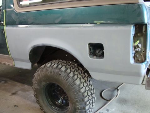 1996 Ford Bronco - Photograph of a Bronco rear quarter panel in primer during paint prep, not a technical document.