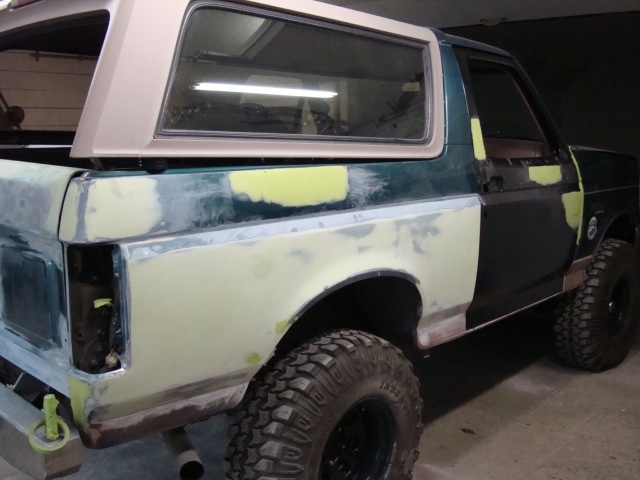 Rear three-quarter of a Bronco in primer and patchy paint during restoration