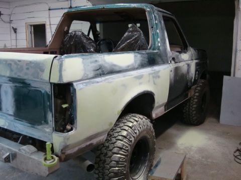 1996 Ford Bronco - Photograph of a lifted Bronco in primer during restoration, not a technical document.