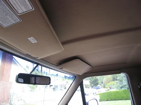 1986 Ford Bronco - The interior of a vehicle shows the headliner, a sun visor with an "AIR BAG" sticker, and a rearview mirror. The view looks out the windshi…
