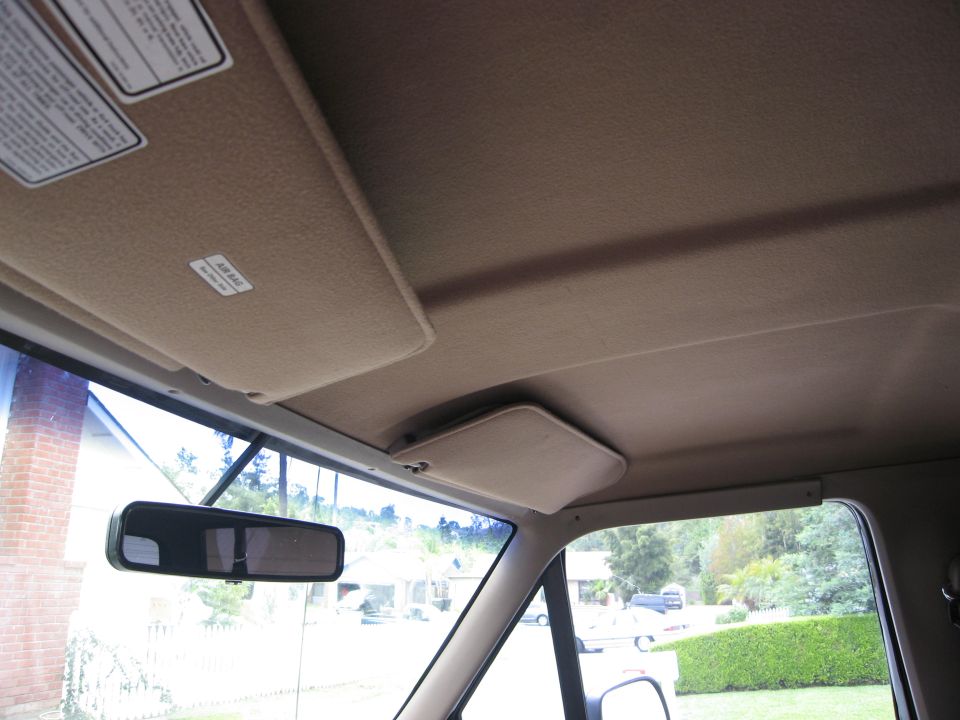 Interior view of a vehicle showing the headliner, sun visor, and rearview mirror.