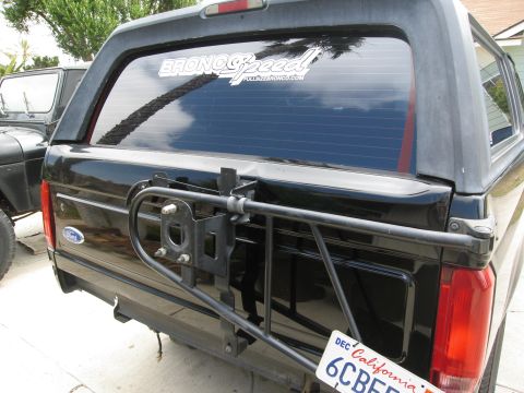 1986 Ford Bronco - The rear view of a black 1986 Ford Bronco shows a spare tire carrier mounted on the tailgate. A "BRONCO Speed" sticker is visible on the re…