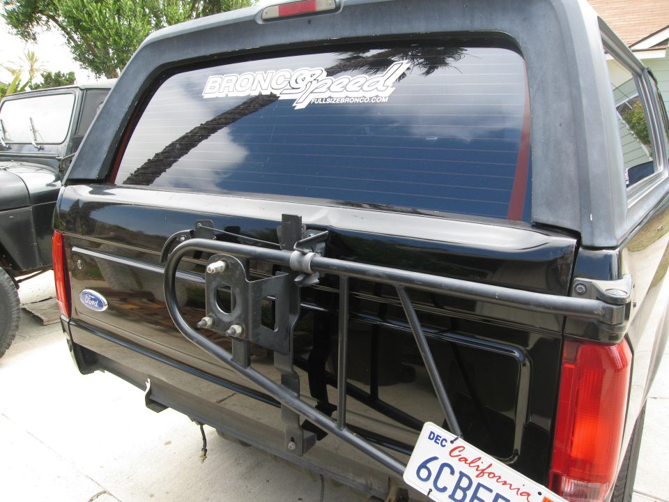 Black 1986 Ford Bronco rear view with spare tire carrier and "BRONCO Speed" sticker on window.