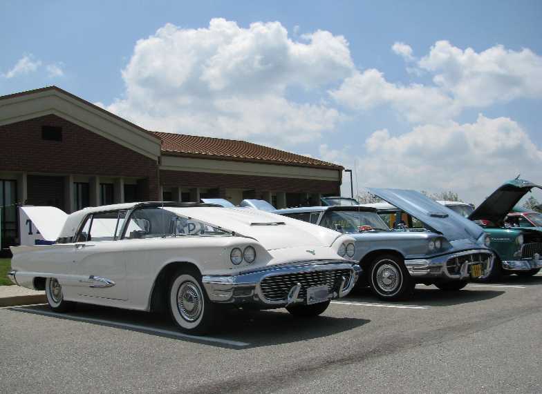 White 1958 Ford Thunderbird convertible with hood and trunk open, parked in a lot