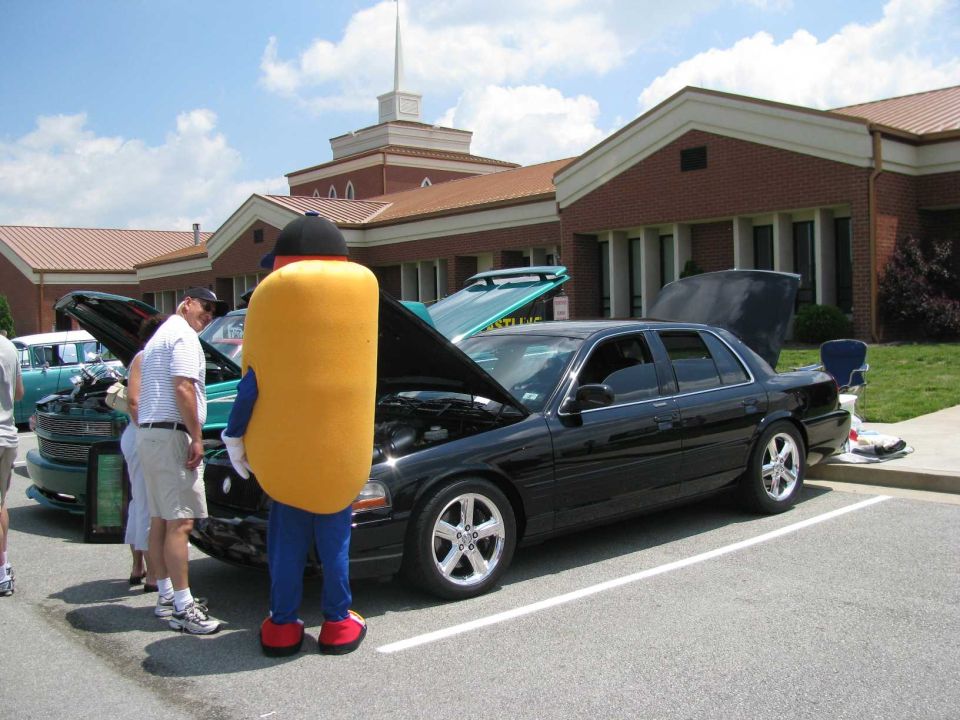 Black 2003 Mercury Marauder with hood open, hot dog mascot nearby