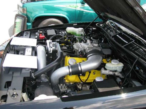 2003 Mercury Marauder - The engine bay of a car is shown, with a green truck in the background.