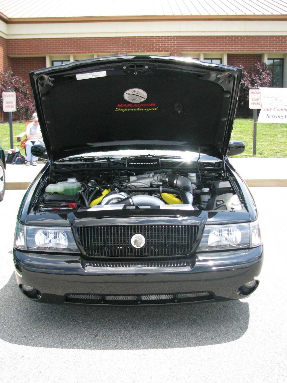 2003 Mercury Marauder front view, hood open, engine visible. Supercharged badging on hood liner