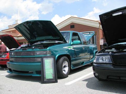 2003 Mercury Marauder - A teal pickup truck with custom graphics is displayed with its hood open, alongside another vehicle.