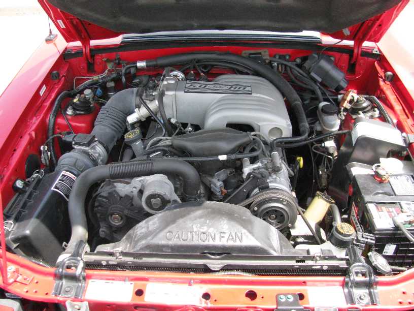 Red engine bay with V8 engine, air intake, and radiator fan