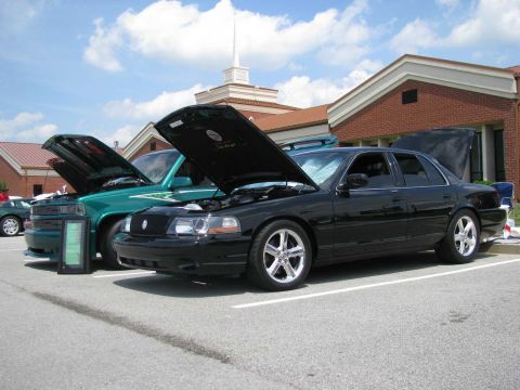 2003 Mercury Marauder - Two vehicles, a black sedan and a green pickup, are displayed with their hoods open at an outdoor event.