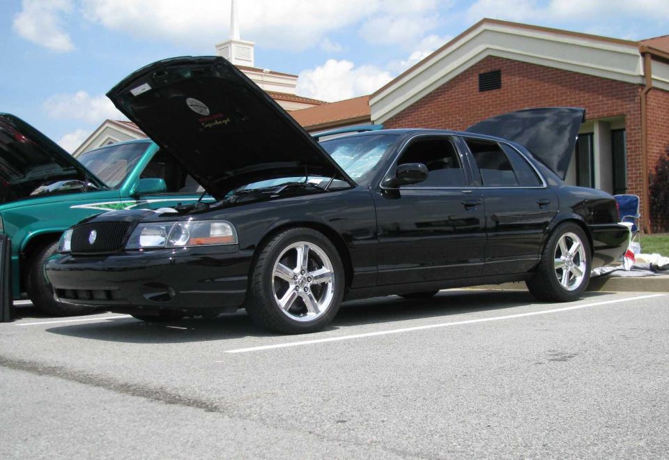 Black 2003 Mercury Marauder with hood and trunk open, parked next to a green truck