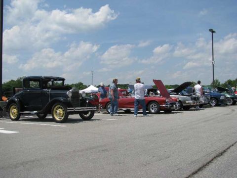 2003 Mercury Marauder - A black coupe with yellow wheels is parked at a car show alongside other vehicles under a cloudy sky.
