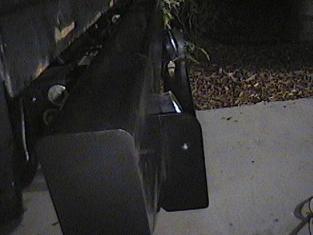 Close-up of a black rear bumper and a tire on a concrete surface