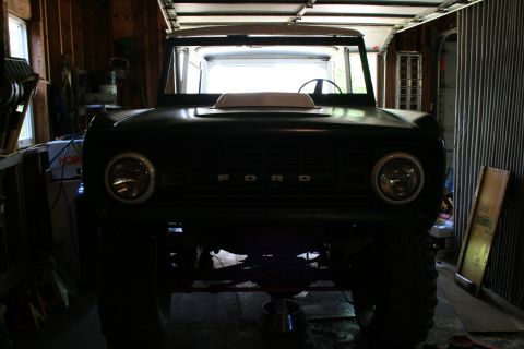 1974 Ford Bronco - The front grille and headlights of a 1974 Ford Bronco are visible, parked inside a garage.