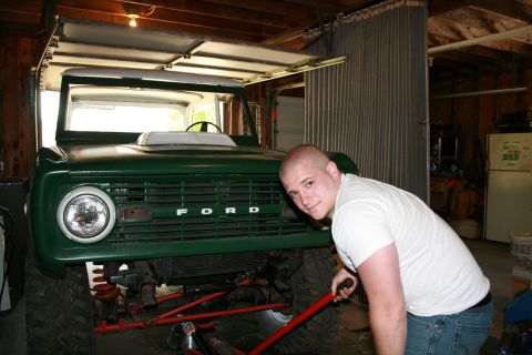 1974 Ford Bronco - Man works on a green 1974 Ford Bronco in a garage.
