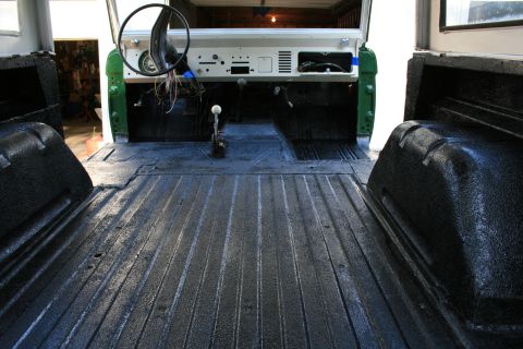 1974 Ford Bronco - The interior of a classic Ford Bronco is shown, a spray-on bed liner and exposed dashboard components.