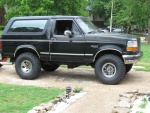 1994 Ford Bronco - A black 1992 Ford Bronco is shown from the side, equipped with a lifted suspension and aftermarket wheels.
