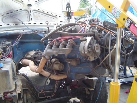 1979 Ford Bronco - The engine is being lifted out of the vehicle's engine bay with a hoist.