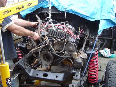 1979 Ford Bronco - Mechanic using an engine hoist to remove the engine from a vehicle chassis during a repair or restoration.