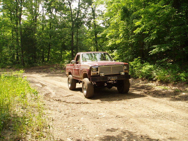 Maroon pickup truck with chrome grille and 'FORD' emblem on dirt road