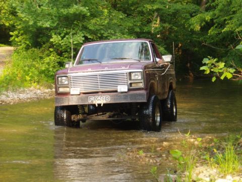 1980 Ford Bronco - This 1980 Ford Bronco is navigating a stream, its front grille clearly visible.
