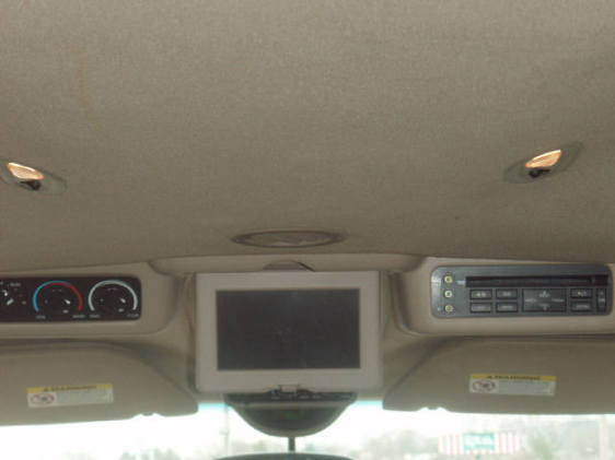 Vehicle interior with overhead screen, climate controls, and stereo system