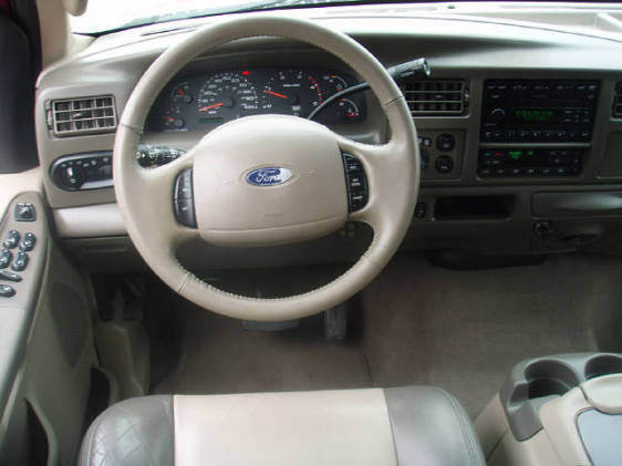 Tan dashboard and steering wheel with Ford logo, showing gauges and radio