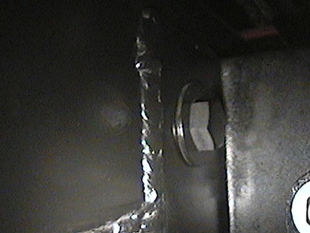 Close-up of a welded steel bracket with a hex bolt on a dark frame