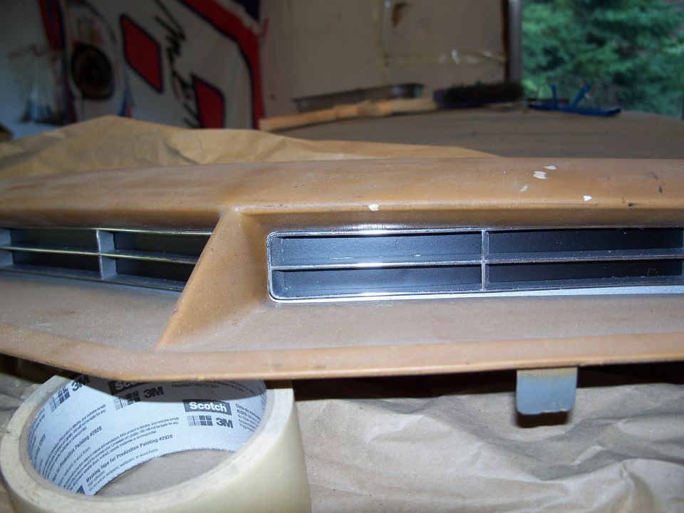 Dashboard vent with chrome trim and horizontal slats, taped off
