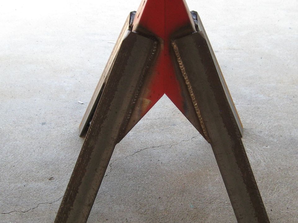 Pair of red and metal jack stands welded together on concrete