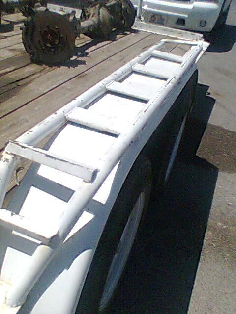 1978 Jeep Cherokee - A white ladder rack is mounted on a trailer, with a rear axle and wheels visible in the background.