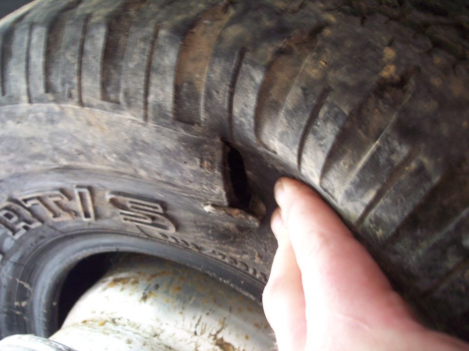 Close-up of a damaged tire with a cut in the sidewall. Text on tire reads 'RTI 3'