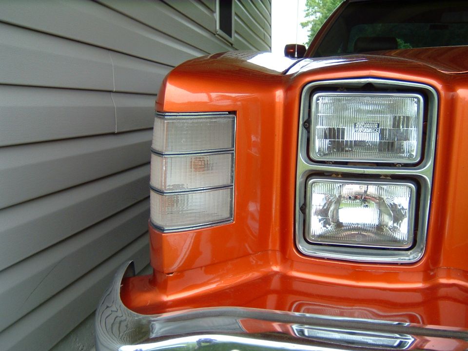 Front corner of an orange car showing stacked headlights and a triple-stacked turn signal