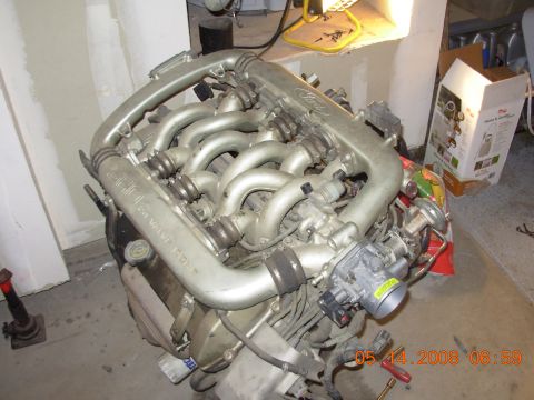 1995 Ford Taurus - A silver 24-valve SHO engine is shown disassembled in a garage setting. The engine is partially covered by a red and white bag, with a card…