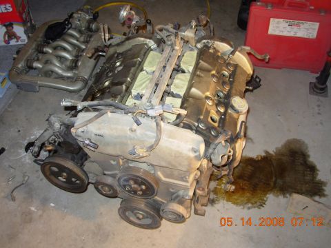 1995 Ford Taurus - A disassembled V6 engine is laid out on a concrete floor, with various parts including intake manifolds, valve covers, and pulleys visible.…