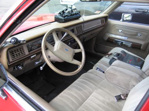 1991 Ford LTD Crown Victoria - interior of a Ford sedan showing a tan cloth bench seat, dashboard and steering wheel with a Ford oval emblem.