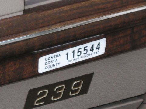 1991 Ford LTD Crown Victoria - Close-up of a woodgrain dashboard with an inventory tag reading CONTRA COSTA COUNTY 115544 DO NOT REMOVE TAG above 239.