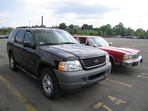 1991 Ford LTD Crown Victoria - black Ford Explorer SUV parked at an angle in a parking lot next to a red sedan.